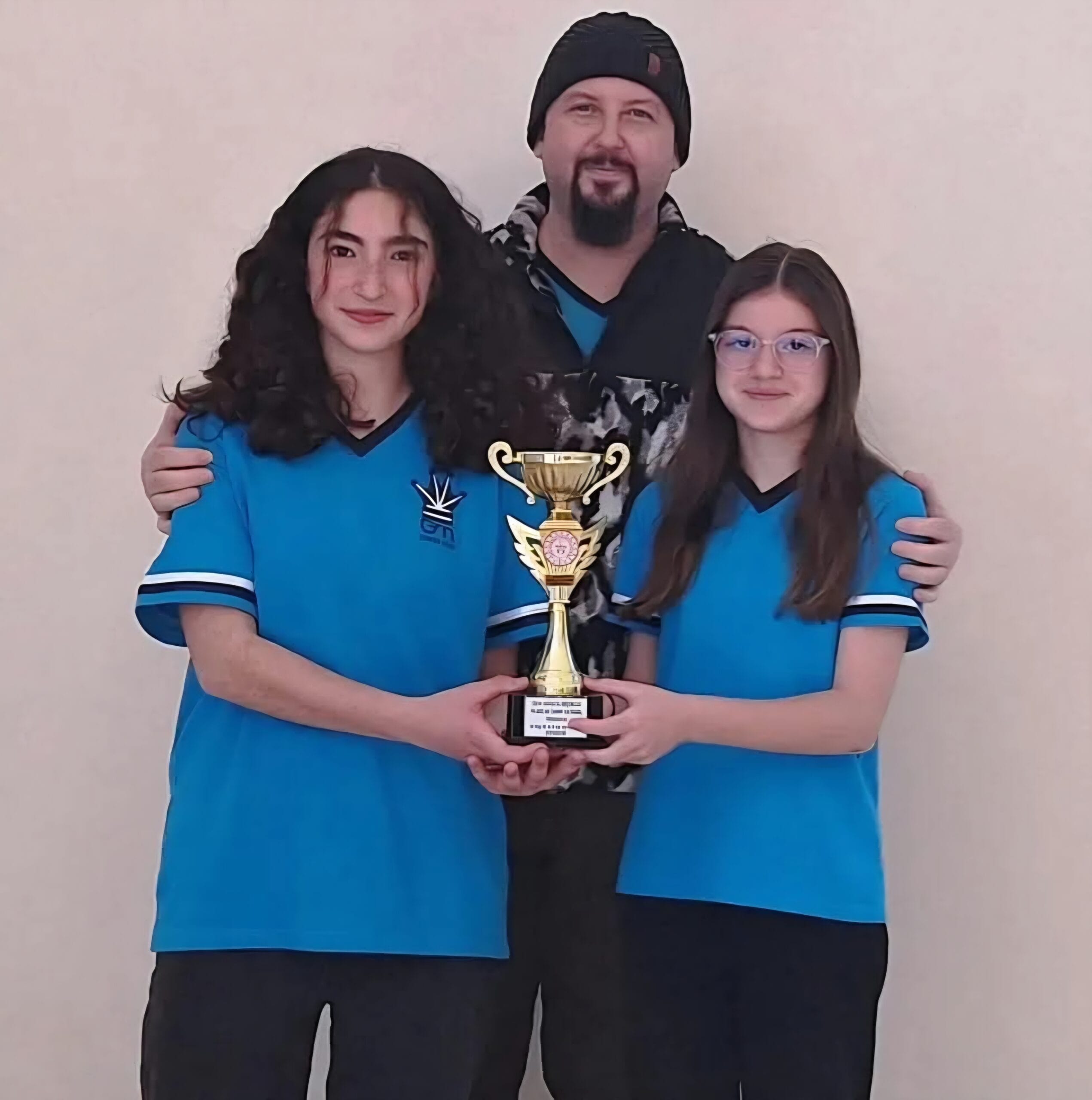 Chess Club Antalya students and coach posing with a championship trophy after a successful tournament