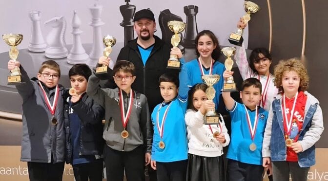 Children and coach celebrating tournament success at Grandmasters Chess Club Antalya