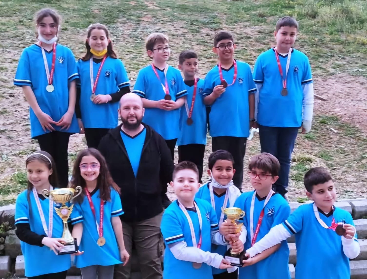 Chess Club Antalya students and coach celebrating tournament success with medals and trophies