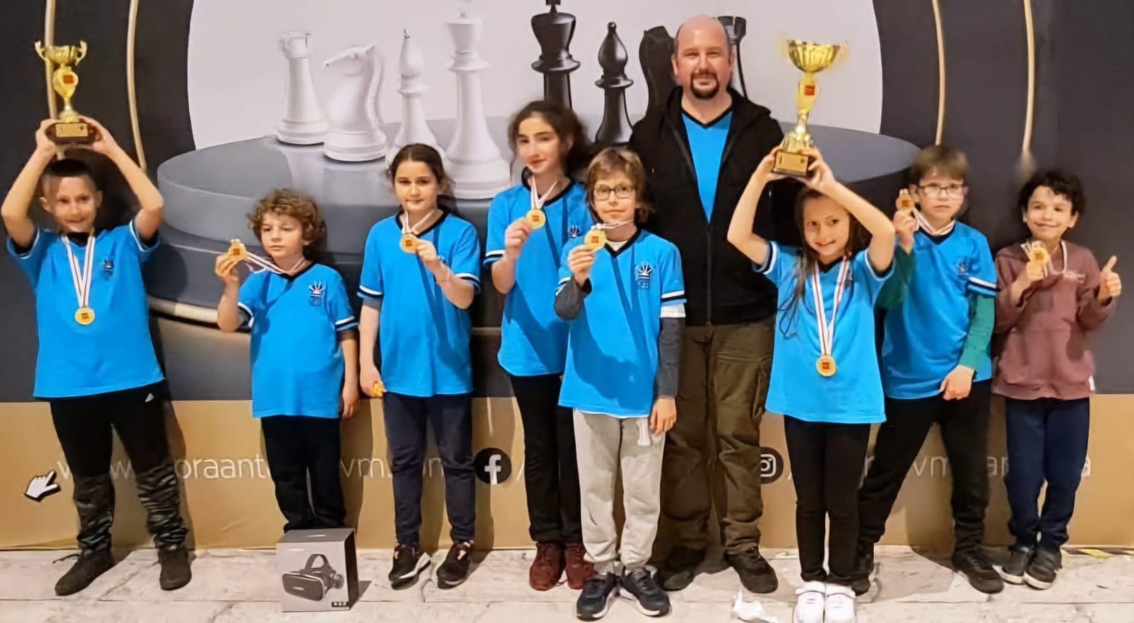 Chess Club Antalya students and coach celebrating tournament success with medals and trophies